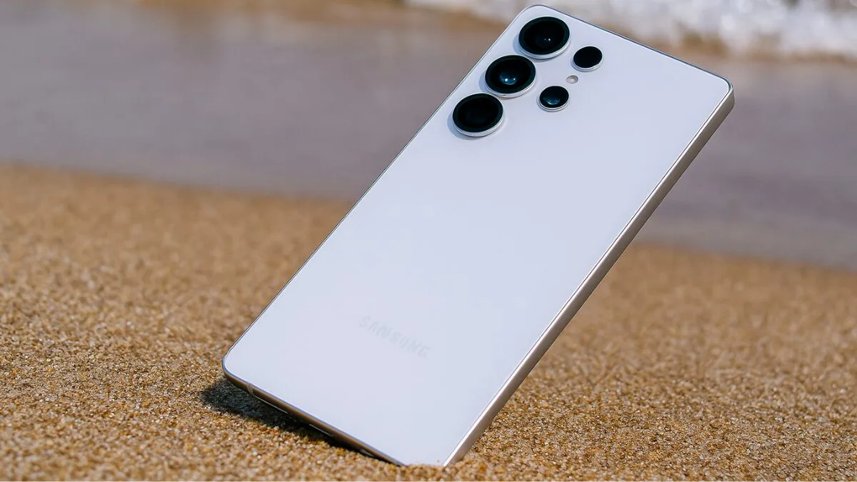 Person holding a Samsung Galaxy S26 Ultra-style phone showing the rear camera array; candid lifestyle shot with blurred city background, logo-free.